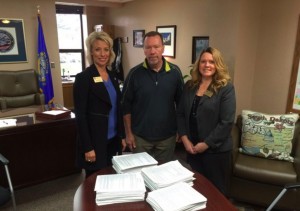 Steven C. Hildebrand (center) delivers a petition with 20,081 signatures to Secretary of State Shantel Krebs (left) and Deputy SOS Kea Warne (right) to place a 36% rate cap on payday and car title loans on South Dakota's 2016 ballot. Photo from Secretary of State's office, 2015.11.05.