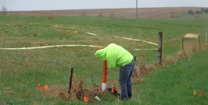 An unidentified worker who arrived in a vehicle marked Summit Utility Services, based in Glasgow, Montana, checks a fiber optic cable access point near the north entrance to the pipeline spill site.
