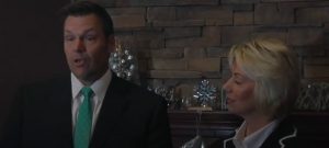 Just closing her eyes to the Trumpist lies... Shantel Krebs with Kris Kobach in Sioux Falls; screen cap from KDLT, 2017.12.14.