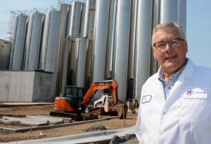 Backhoe prepares to install wheels on Agropur milk silos; from Lon Tonneson, "South Dakota Says 'More Cheese'," Dakota Farmer, 2018.09.24.